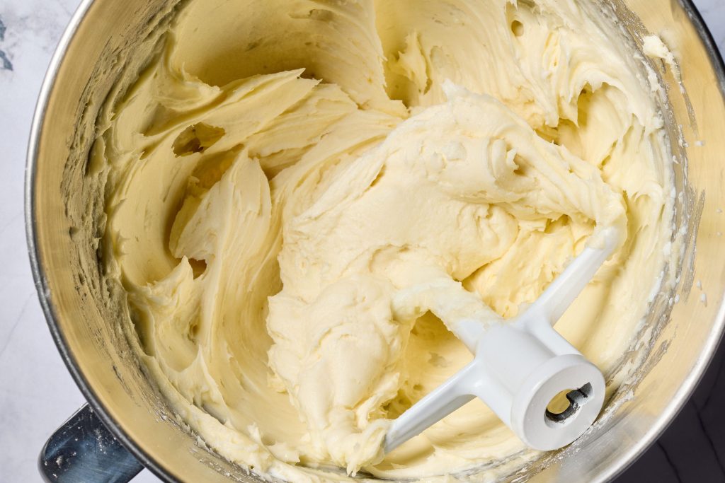 Stand mixer bowl filled with whipped cream cheese frosting and a paddle attachment