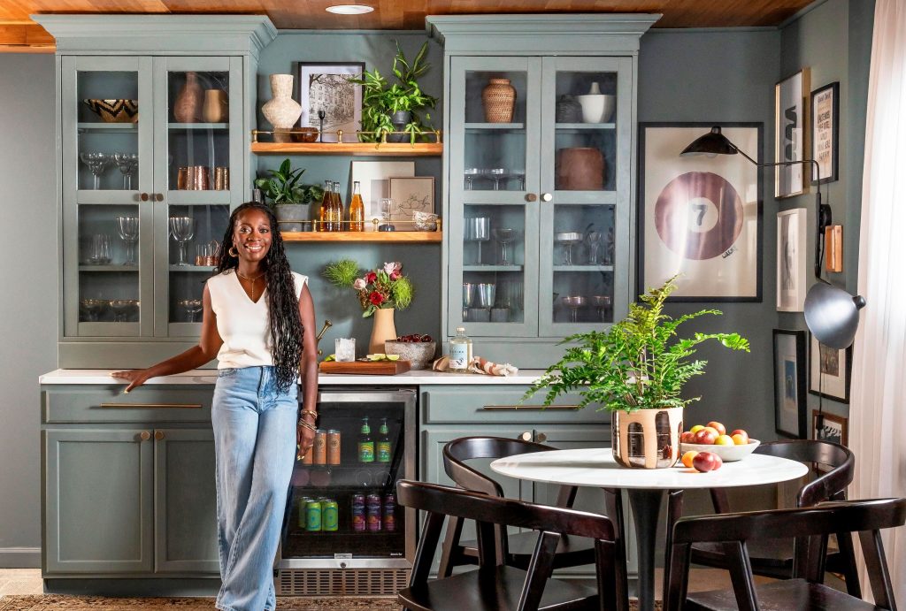 Yinka Davies standing in a modern kitchen space with cabinets and a dining area