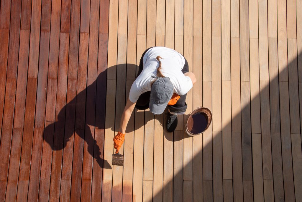 woman staining deck with brush