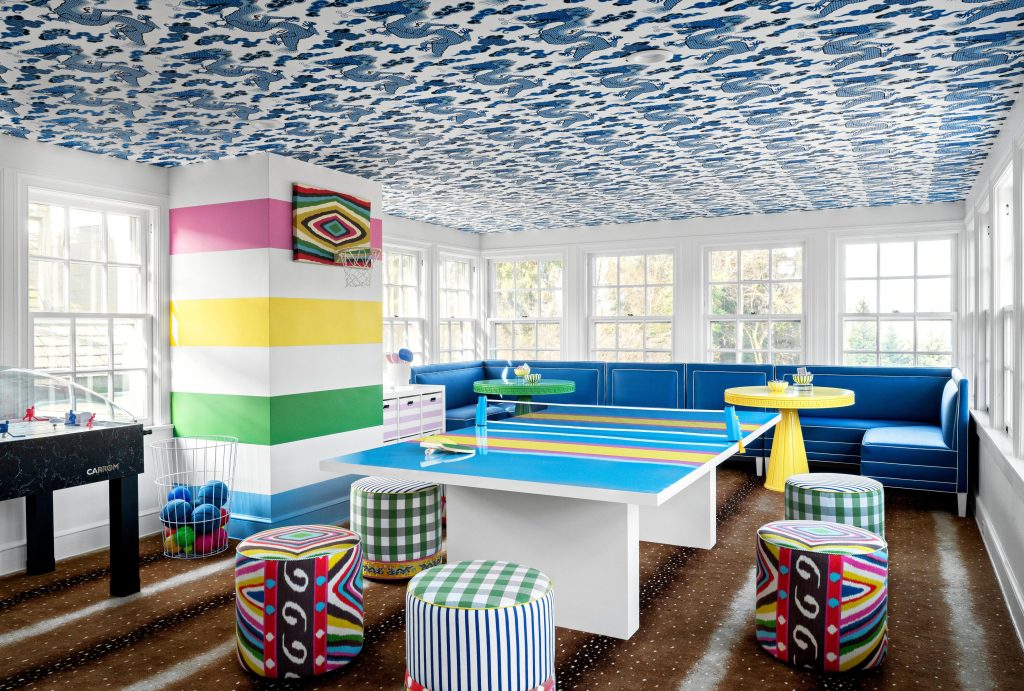 Game room with a pool table benches stools and colorful decor