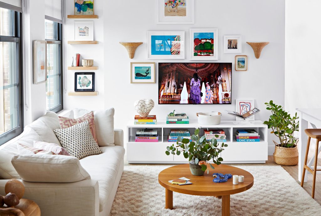 A cozy living room with a sofa coffee table and a TV stand displaying books and dcor decorated with wall art and indoor plants