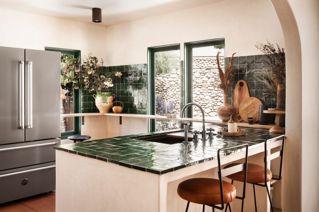 Modern kitchen with green tiled counters and backsplash stainless steel appliances and decorative items on counters