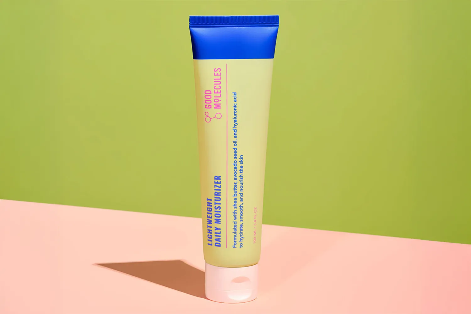 A tube of Good Molecules Lightweight Daily Moisturizer on a colored surface