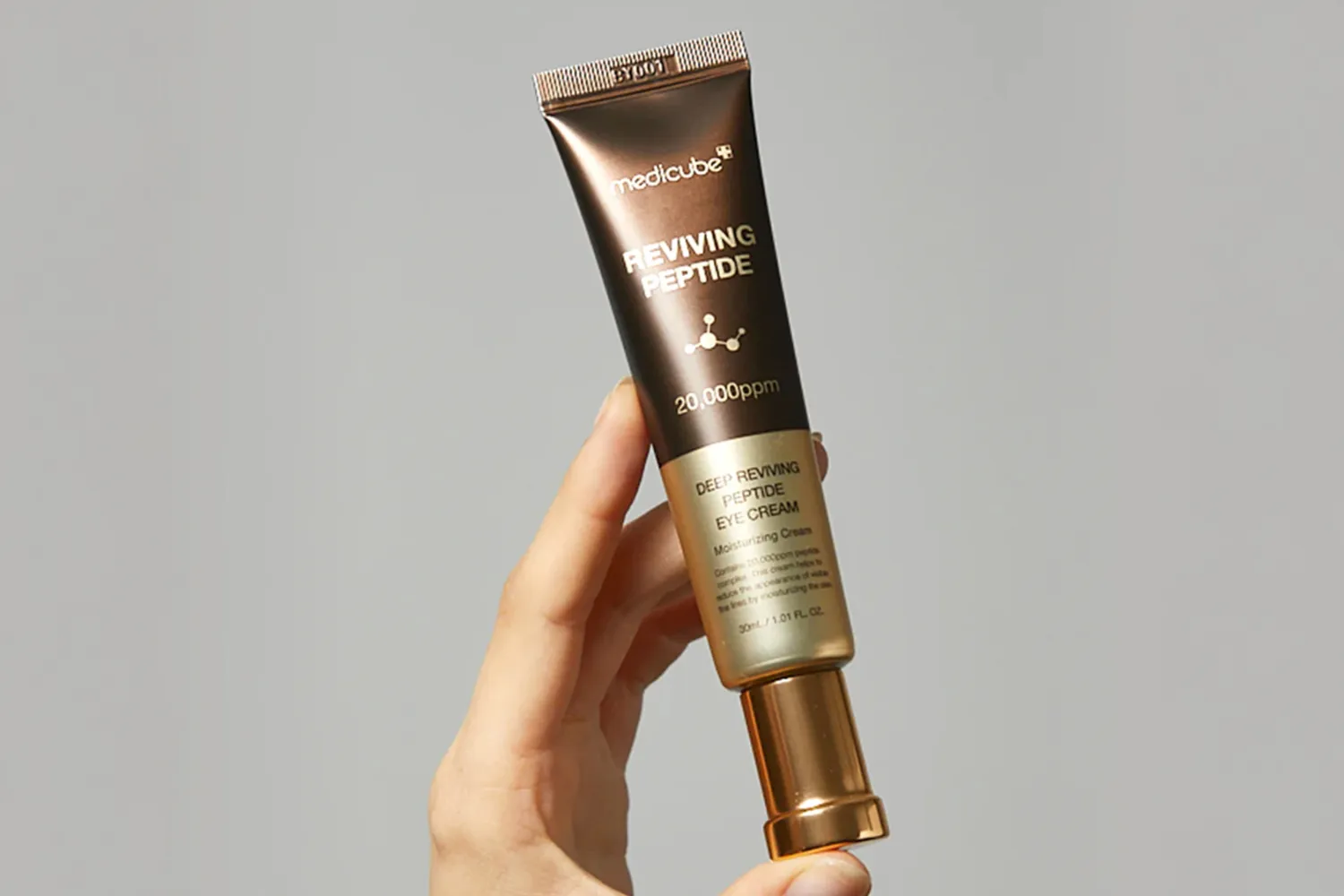 Hand holding a tube of Medicube Reviving Peptide Eye Serum