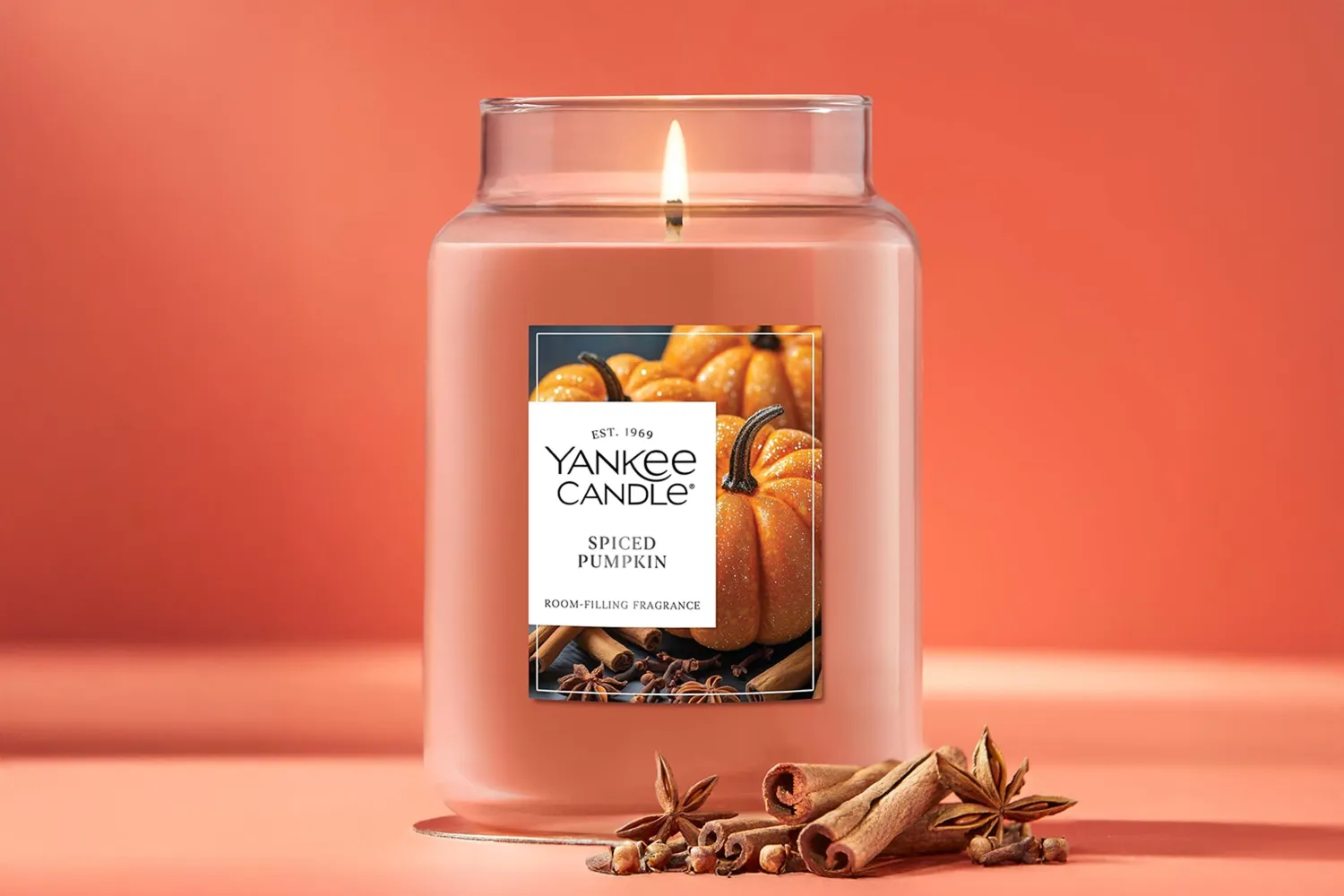 A Yankee Candle jar labeled Spiced Pumpkin with cinnamon sticks and star anise in front of it
