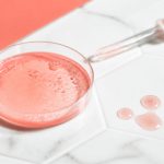 Pink liquid displayed with dropper in white marble tile surface for daily skin care routine for glowing skin