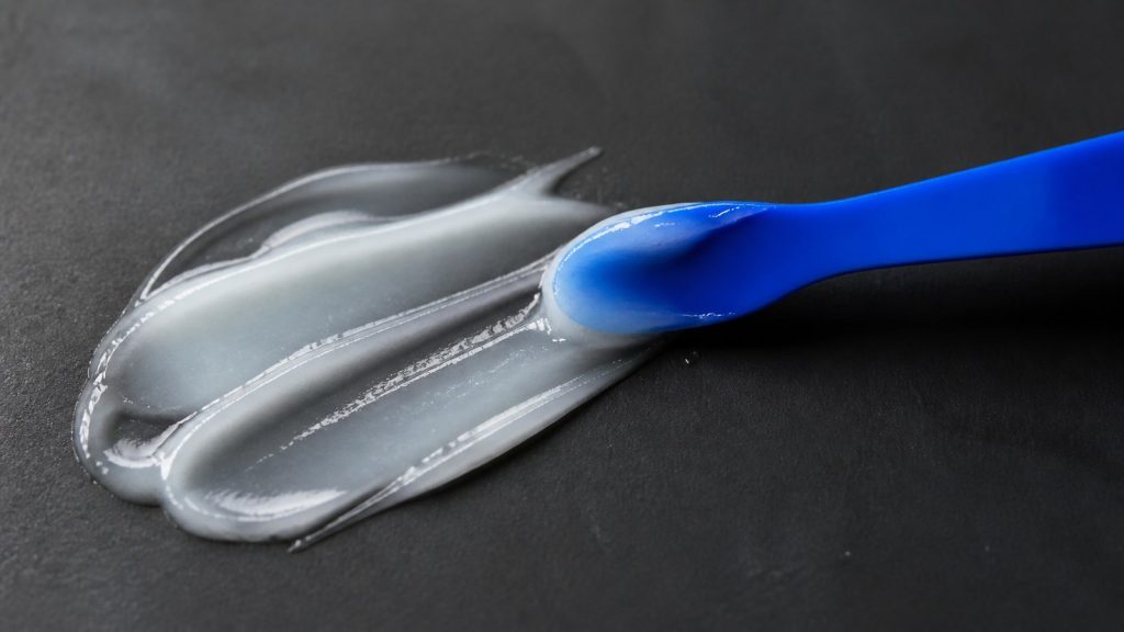 Spreading gel with spatula in dark tabletop for skin barrier repair for oily dehydrated skin