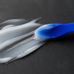 Spreading gel with spatula in dark tabletop for skin barrier repair for oily dehydrated skin