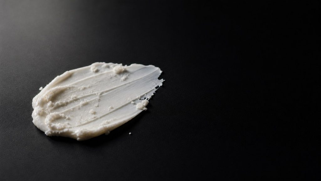 White cream smeared in black textured surface for skincare pilling