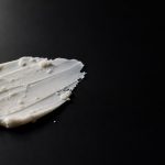 White cream smeared in black textured surface for skincare pilling