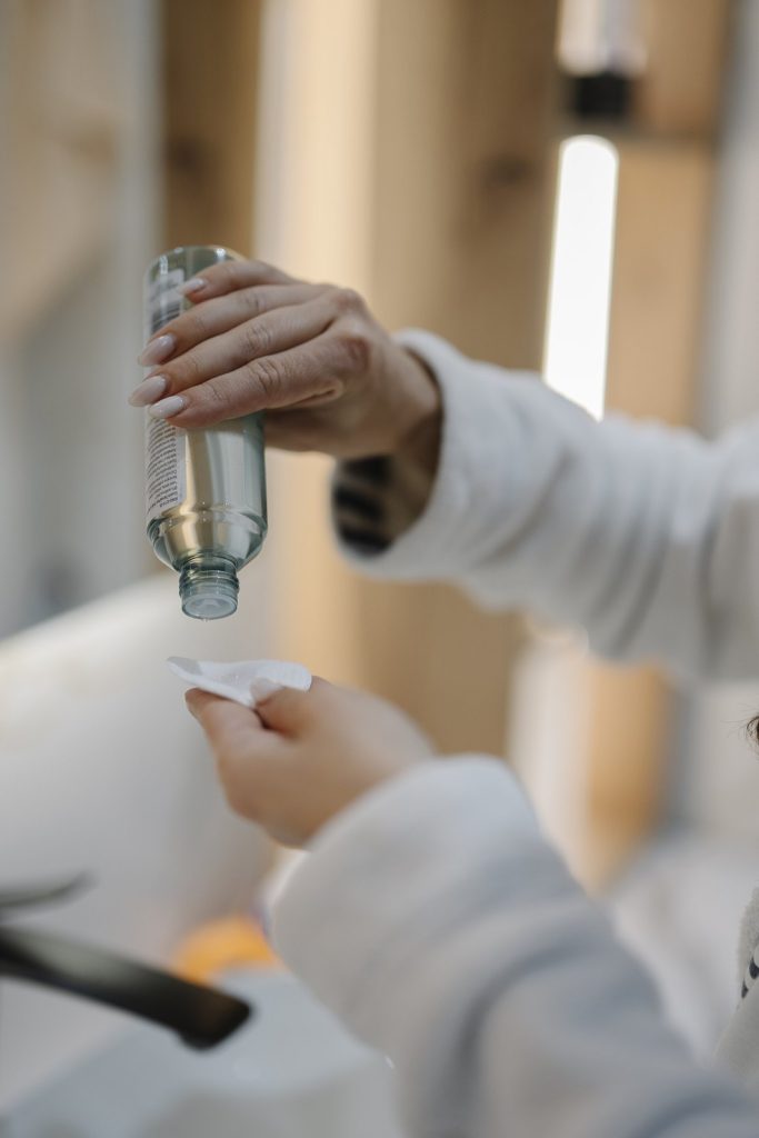 Person pours liquid from a bottle onto a tissue in a bright indoor space.jpg
