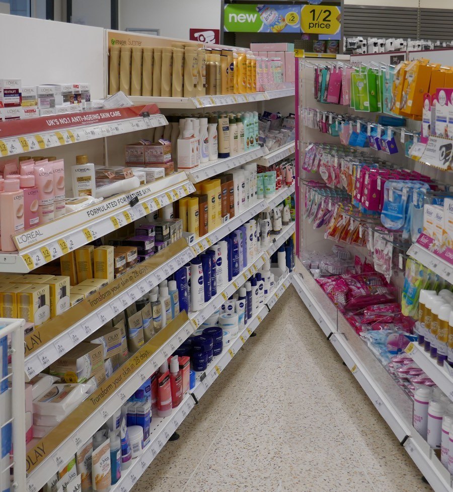 Drugstore skincare aisle with branded facial creams, lotions, cleansers, and personal-care products