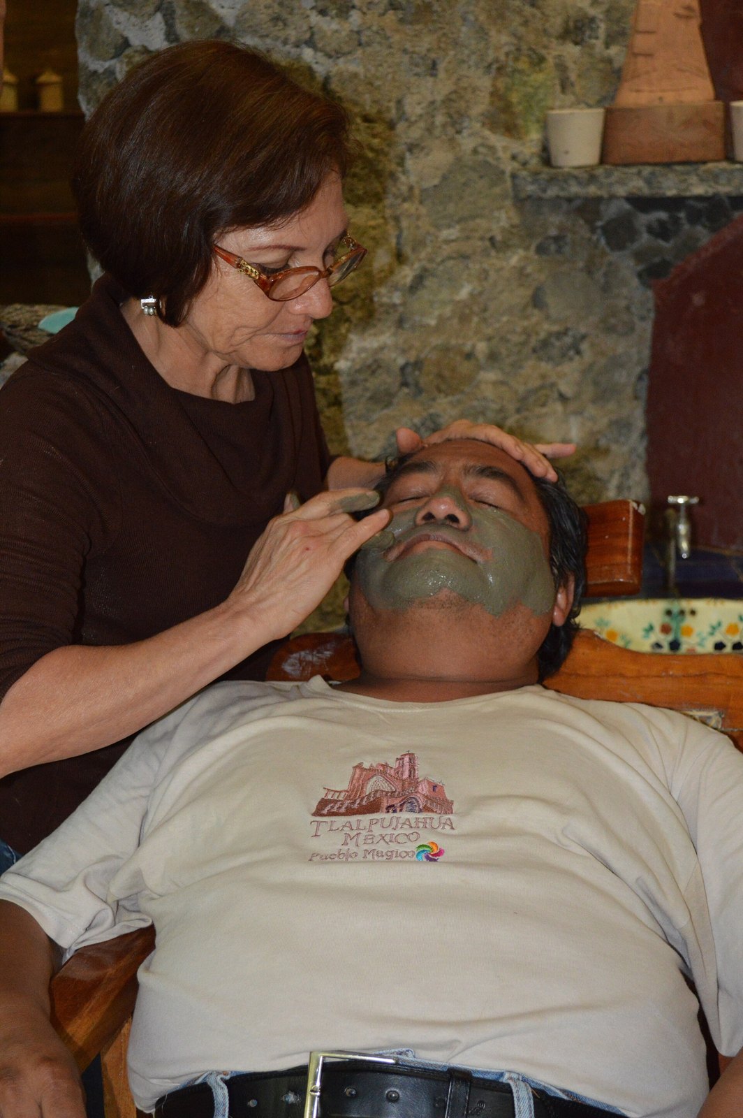 Person receiving a green clay facial mask application