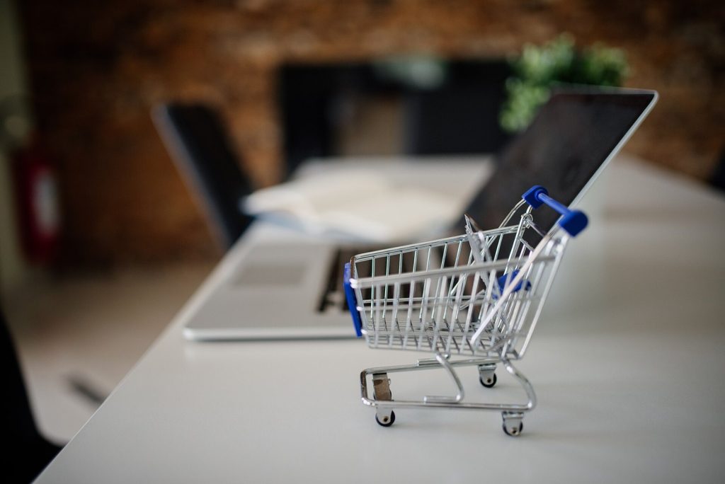 Miniature shopping cart beside a laptop